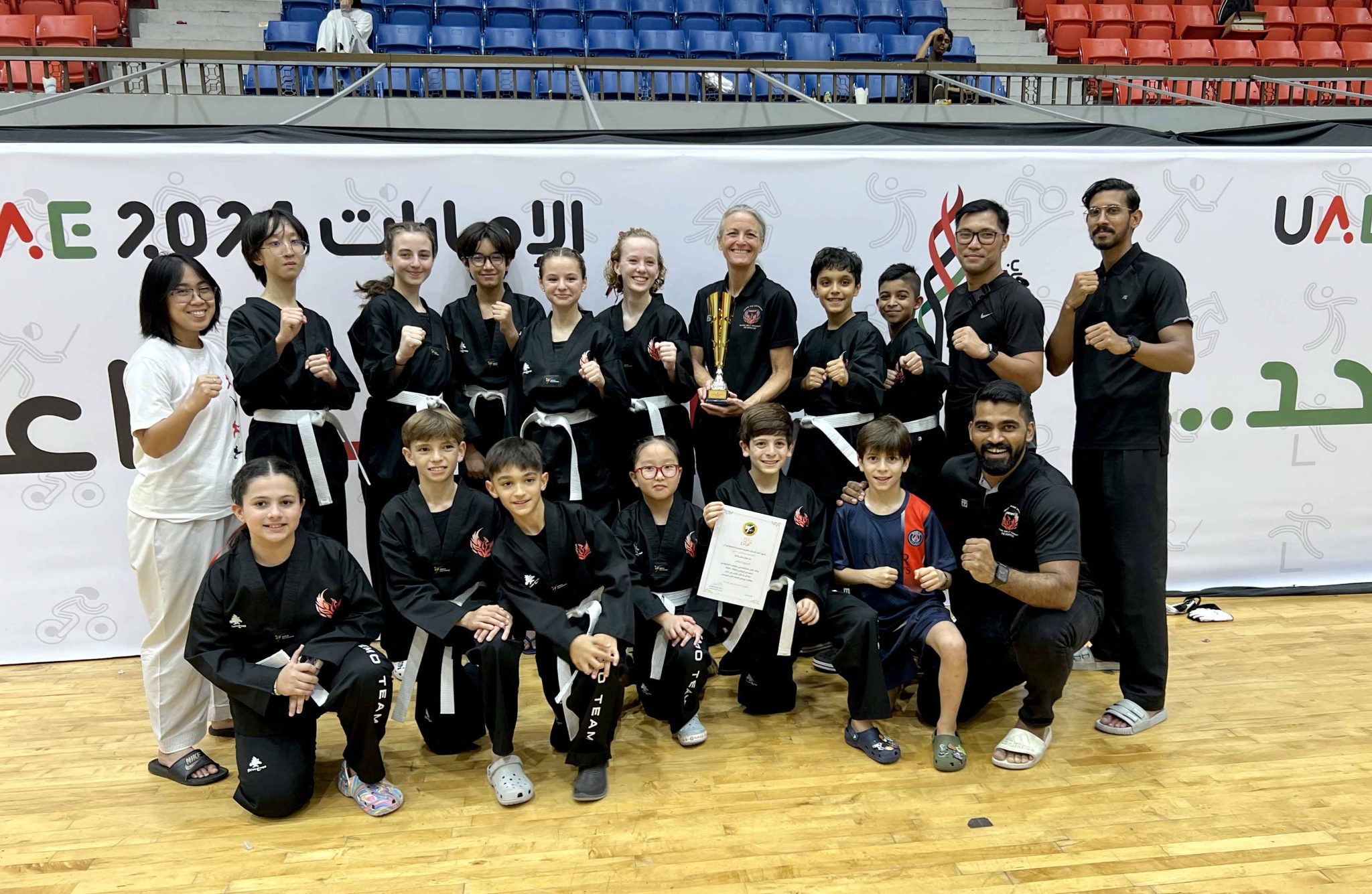 Phoenix Black Belt Academy students and instructors with a trophy at a UAE martial arts event