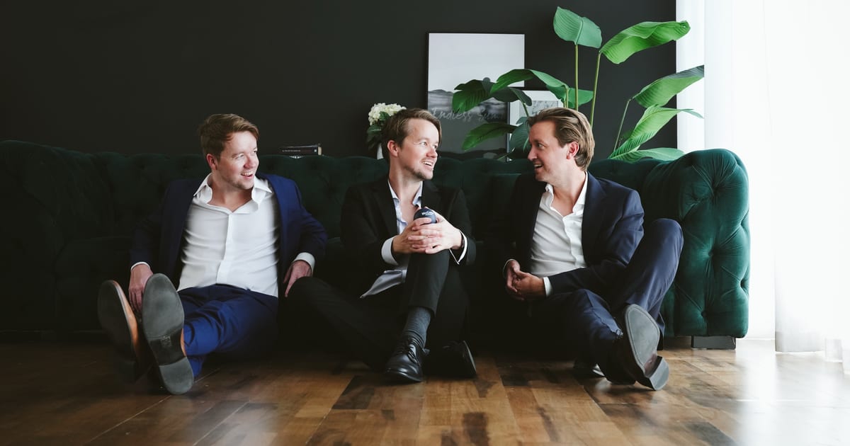 Three McCone Properties team members seated on a green sofa in the office, The Greens, Dubai