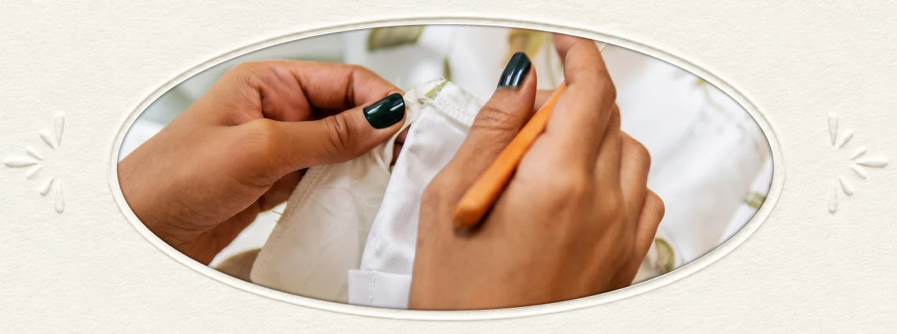Tailor hand-stitching a white garment at The Sewing Corner
